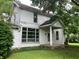 A white two-story home with large windows and a columned front porch nestled among lush trees at 18229 Moontown Rd, Noblesville, IN 46062