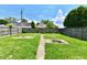 Large backyard featuring a fire pit, grass, and a wooden fence under a partly cloudy sky at 209 E John St, Alexandria, IN 46001