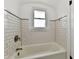 White subway tile surrounds a tub with window and sleek fixtures at 209 E John St, Alexandria, IN 46001