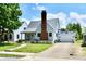 Charming home with blue siding, gray metal roof, red brick chimney, and a white garage at 209 E John St, Alexandria, IN 46001
