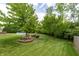 Grassy backyard featuring mature trees and a circular fire pit with chairs for entertaining at 2096 Whitetail Ct, Avon, IN 46123