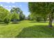 Spacious backyard with lush green grass, mature trees, and a trampoline for outdoor fun and recreation at 321 4Th E Ct, Carmel, IN 46033