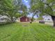 Green backyard with a red outbuilding and mature trees at 3526 E Vermont St, Indianapolis, IN 46201