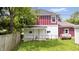 Charming backyard featuring a two-story home with red and white vertical siding, a lawn and partial fence at 541 Dayton Ave, Indianapolis, IN 46203