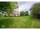 Large backyard with lush green lawn, mature trees, and an iron fence for privacy at 5883 Sandalwood Dr, Carmel, IN 46033
