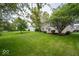 A beautifully landscaped backyard with a spacious lawn, mature trees, and a wooden deck at 5883 Sandalwood Dr, Carmel, IN 46033