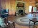Cozy living room with stone fireplace, wood paneling, and an inviting braided rug at 622 S Washington St, Morristown, IN 46161