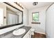 Well-lit bathroom with a dark granite countertop, framed mirror, and a window offering natural light at 6580 Kings Ct, Avon, IN 46123