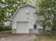 This two-story garage includes a large garage door, a pedestrian door, and exterior lighting at 70 Fairground St, Franklin, IN 46131