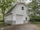 This two-story garage includes a large garage door, a pedestrian door, and a gravel driveway at 70 Fairground St, Franklin, IN 46131
