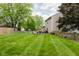 Large backyard with vibrant green lawn, complemented by mature trees and a charming wooden fence at 7402 Northfield Blvd, Fishers, IN 46038