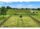 Green lawn with a central tree, enclosed by a wooden fence, featuring a distant shed and field at 7447 S 25 E, Pendleton, IN 46064