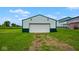 Exterior of a white and green outbuilding with a rolling garage door nestled on a grassy area at 7447 S 25 E, Pendleton, IN 46064