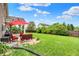 Backyard featuring a red umbrella, seating, grill, covered patio and green lawn at 916 Settlers Walk, Brownsburg, IN 46112