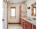 Bathroom showcasing reddish-brown cabinetry, white tile flooring, and a window, offering a blend of style and practicality at 9601 Irishmans Run Ln, Zionsville, IN 46077
