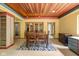 Dining room with wood ceiling, hardwood table and chairs sitting on a zebra rug with an opening to another room at 9601 Irishmans Run Ln, Zionsville, IN 46077