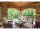 An outdoor living space on a covered porch featuring wicker furniture and stone arches at 9601 Irishmans Run Ln, Zionsville, IN 46077