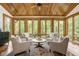 Cozy sunroom with wood ceiling, surrounding windows, and comfortable seating area with nature views at 9601 Irishmans Run Ln, Zionsville, IN 46077