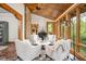 Bright sunroom with wood ceiling, brick wall, and seating with surrounding views of lush greenery at 9601 Irishmans Run Ln, Zionsville, IN 46077