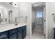Bathroom showcasing a blue vanity with a marble countertop and a tiled shower with glass doors at 9973 Woods Edge Dr, Fishers, IN 46037