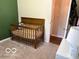 Cozy bedroom with a wooden crib, light carpet, and soft lighting, creating a warm and inviting space at 101 E Hill Valley E Dr, Indianapolis, IN 46227