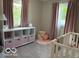 Charming bedroom with pink accents, showcasing a crib and organized storage shelves at 101 E Hill Valley E Dr, Indianapolis, IN 46227