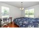 Well-lit bedroom with two windows, wood floors, and a dedicated workspace with desk and chair at 12772 Tram Ln, Carmel, IN 46032