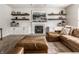 Inviting living room featuring a cozy fireplace, stylish floating shelves, and a comfortable leather sectional sofa at 14149 Ledgewood Way, Carmel, IN 46032