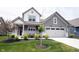 Inviting two-story home showcasing a well-kept lawn, charming front porch with seating, and an attached garage at 19800 Sutton Ter, Westfield, IN 46074