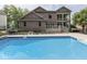 Large backyard swimming pool view including brick home exterior and upper level sunroom at 20 Forrests Edge Ct, Indianapolis, IN 46227