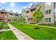 Exterior showcasing townhomes, green grass, landscaped areas, and a sidewalk through the community at 2125 Coretta Way, Indianapolis, IN 46202