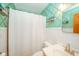 Compact bathroom featuring a vanity, toilet, shower with white curtain, and decorative wallpaper at 3004 Sheridan St, Anderson, IN 46016