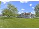 Spacious backyard showing the house's back exterior and the ample grassy area with mature tree at 310 W Jackson St, Alexandria, IN 46001