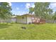 A grassy backyard with a wood deck attached to a beige home under a blue sky at 3898 S Randolph St, Indianapolis, IN 46227