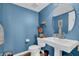 Stylish powder room with blue walls, pedestal sink, round mirror, and modern fixtures at 4157 Taunton Ct, Plainfield, IN 46168