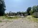 View of a partially collapsed building surrounded by gravel, vegetation, and trees on a clear day at 4566 Melbourne Rd, Indianapolis, IN 46228