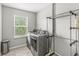 Well-lit laundry room with modern silver appliances, a window, and convenient shelving for storage at 4642 Big Run Ct, Indianapolis, IN 46239