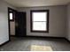 A bedroom featuring neutral walls, dark trim, a dark door, plush carpet and a bright window at 509 Shelby St, Shelbyville, IN 46176