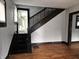 Elegant staircase featuring dark wood and white walls leading to the upper level, with glimpses of the kitchen at 509 Shelby St, Shelbyville, IN 46176
