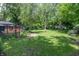 Backyard featuring green lawn, brick patio, lush landscaping, and mature trees at 5315 Camden St, Indianapolis, IN 46227