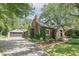 A brick home with lush greenery, a detached garage, and a long driveway are featured at 5315 Camden St, Indianapolis, IN 46227