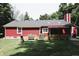 Exterior shot of a home with red siding, a striped awning over the patio, and a well-kept lawn at 5654 Paradise Dr, Martinsville, IN 46151
