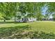 View of the backyard featuring lush green grass, mature trees, and a cozy covered patio at 5710 W 650 N, Thorntown, IN 46071