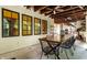 Covered outdoor patio with a long table and chairs for dining, featuring wood beams and outdoor lighting at 5805 Forest Ln, Indianapolis, IN 46220