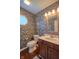 Unique half-bathroom featuring vibrant wallpaper, decorative mirror, and marble countertop sink at 6483 Royal Oakland Dr, Indianapolis, IN 46236