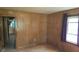 Hardwood floors, wood paneled walls, and view into the kitchen in this modest bedroom at 6484 S State Road 39, Clayton, IN 46118