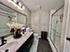 Bathroom with dual sink vanity, framed mirror, panelled accent wall, and glass-enclosed shower at 6927 Havenmoor Pl, Indianapolis, IN 46250