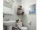 Bathroom featuring pedestal sink, wire baskets with rolled towels, toilet, and modern artwork at 762 N Dellasburg Rd, Columbus, IN 47203