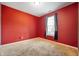 A cozy bedroom with a red accent wall, plush carpet and a window providing plenty of natural light at 8199 Sydney Ln, Avon, IN 46123