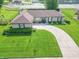 Aerial view of brick ranch home on manicured lot with curved driveway, mature trees, and front garden at 8209 Burn Ct, Indianapolis, IN 46217